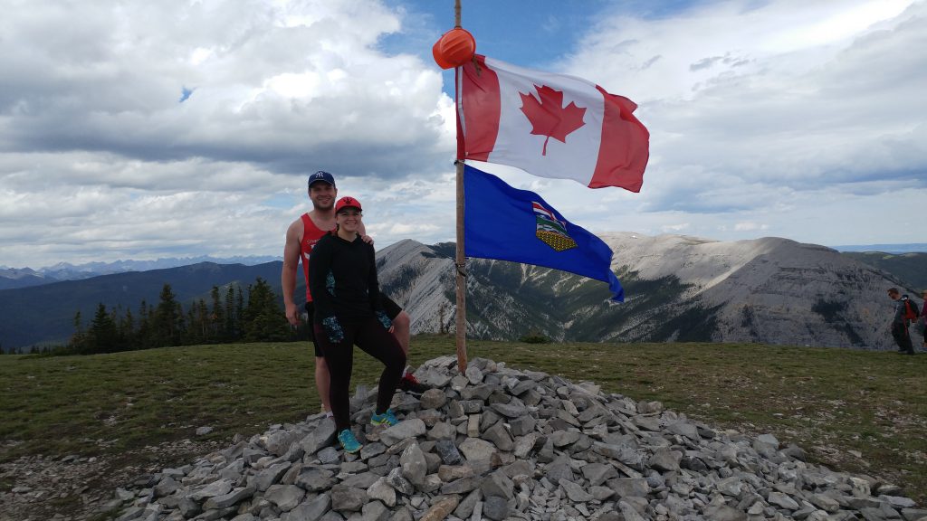 An image of two people standing at the top of Prairie Mountain in Alberta, Canada