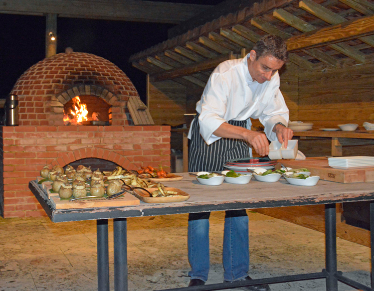 An image of Executive Chef Christophe Letard preparing dinner under the stars in the gardens at Belle Mont Farm