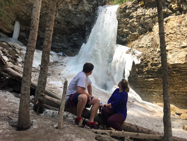 An image of a couple looking back at Troll Falls in Kananaskis, Alberta