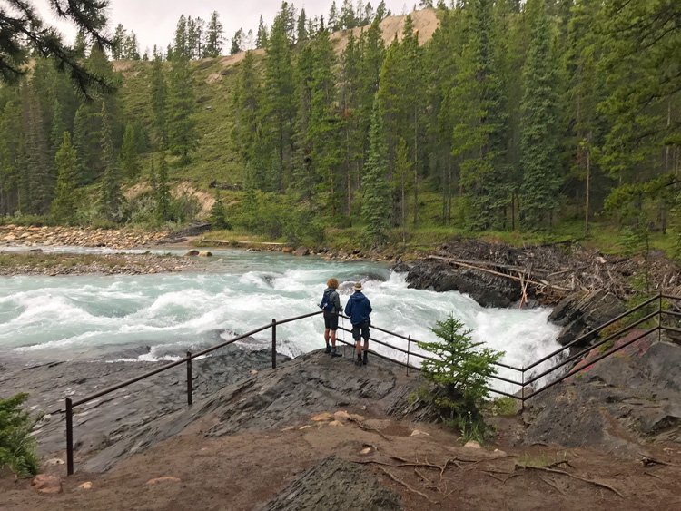 An image of a couple overlooking the top of Siffleur Falls in Alberta, Canada. 