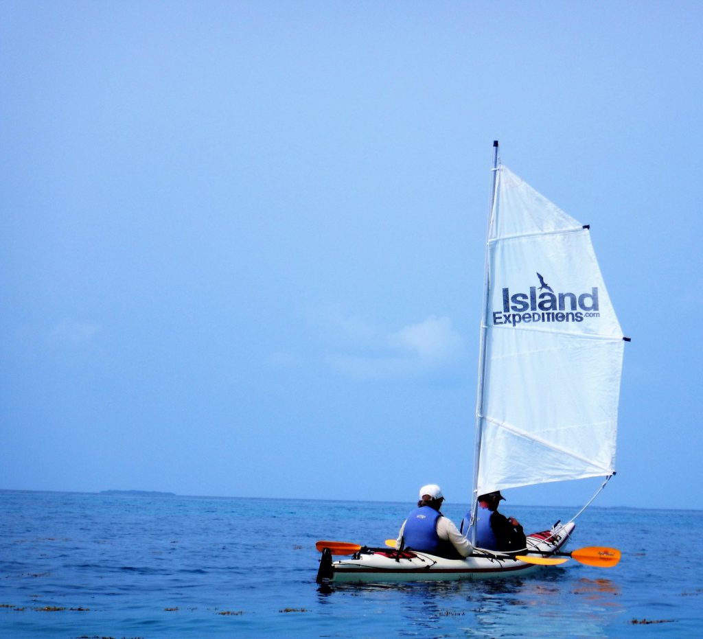 Image of a two paddlers in a double kayak with a sail in Belize