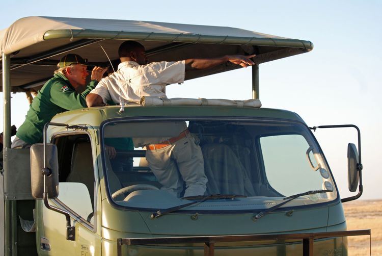 An image of a man looking through binoculars on a guided safari in Namibia, Africa