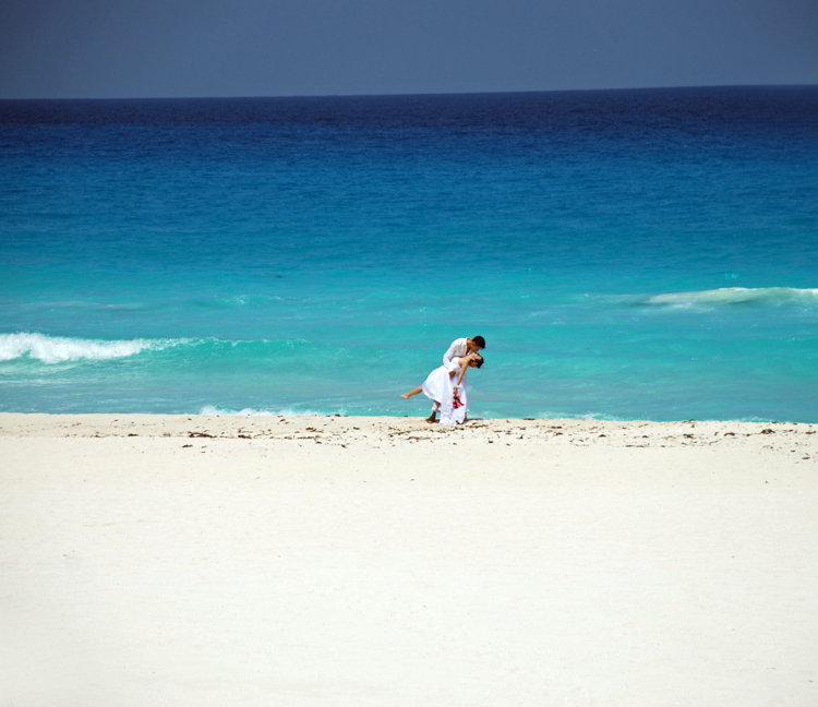 An image of a bride and groom kissing on a beach in Cancun, Mexico