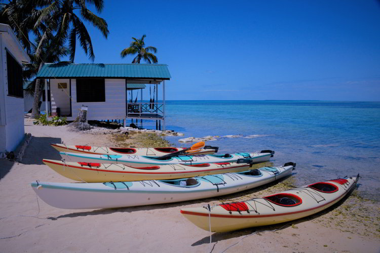 An image of four kayaks on the beach at Tobacco Caye Paradise Resort in Belize