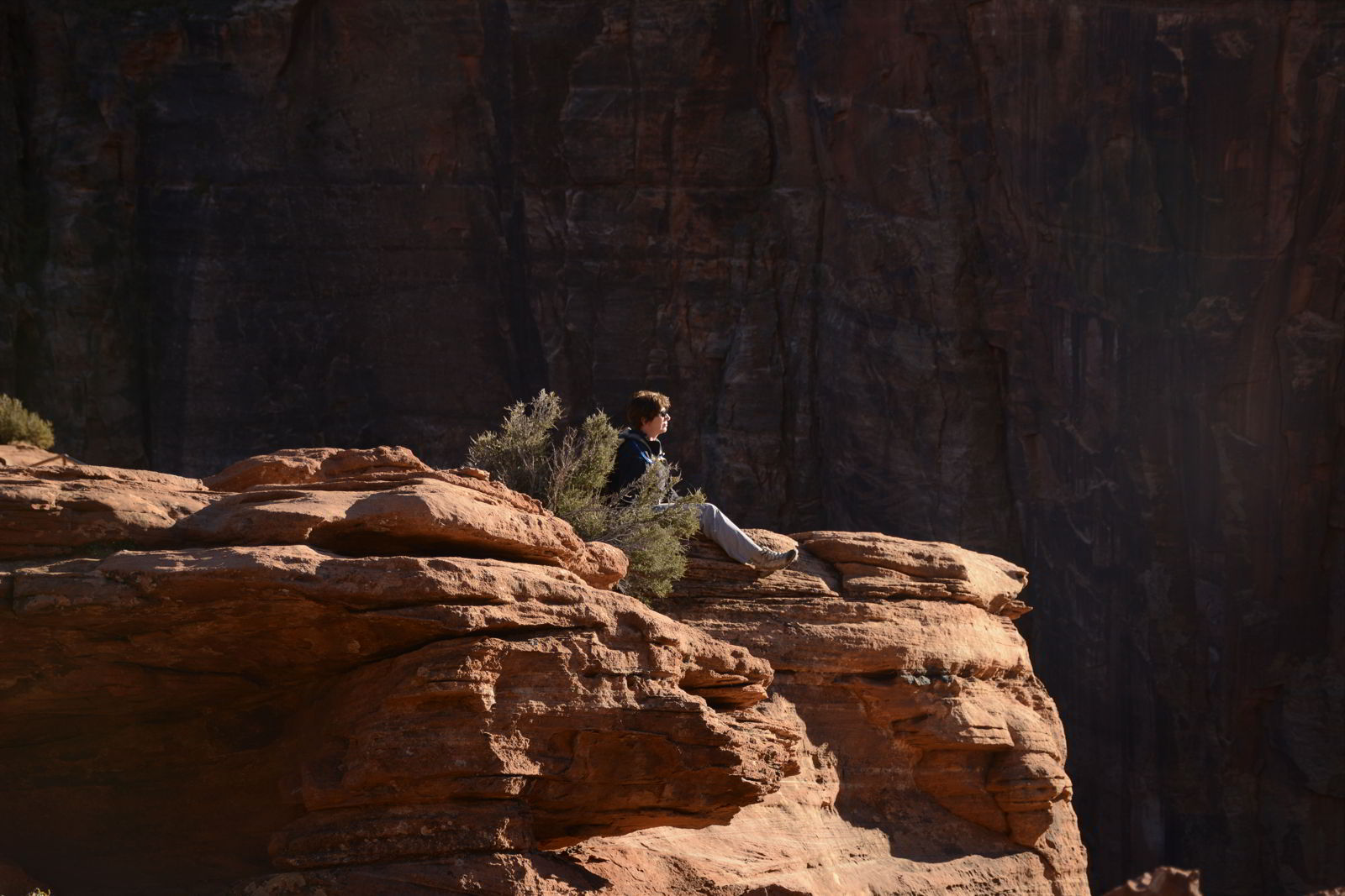An image of the author sitting on a cliff watching the sunset at Canyon Overlook in Zion National Park in Utah - Best Zion National Park Hikes