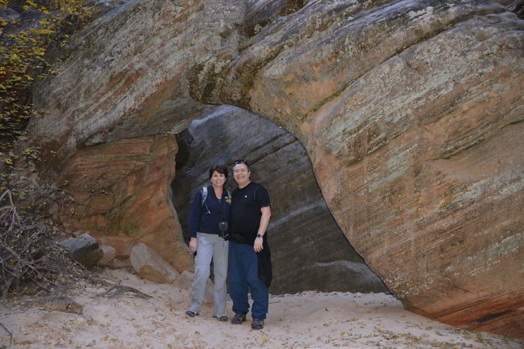 An image of two people standing under the arch on the Hidden Canyon Trail in Zion National Park in Utah - Best Zion National Park Hikes