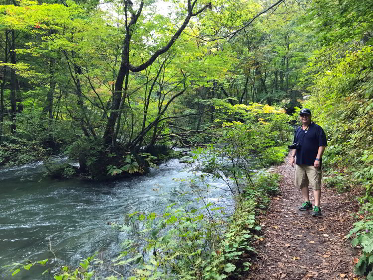 An image of a man standing on the trail beside Oirase Stream near Aomori, Japan - Lake Towada and Oirase Gorge