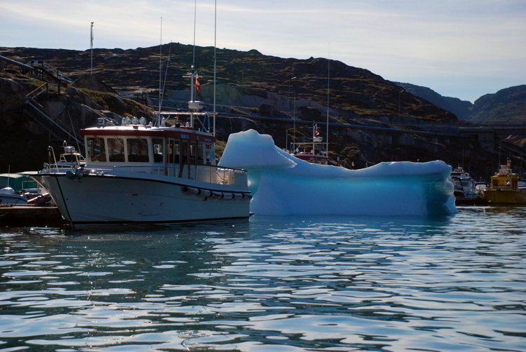 An image of a boat and an iceberg in Ilulissat Harbor - Ilulissat Greenland