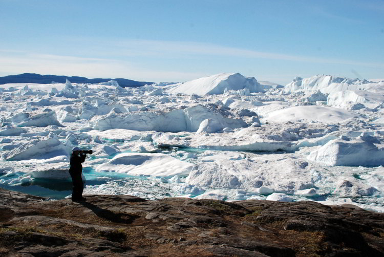 An image of a photographer taking a picture of the Ilulissat Icefjord in Ilulissat Greenland