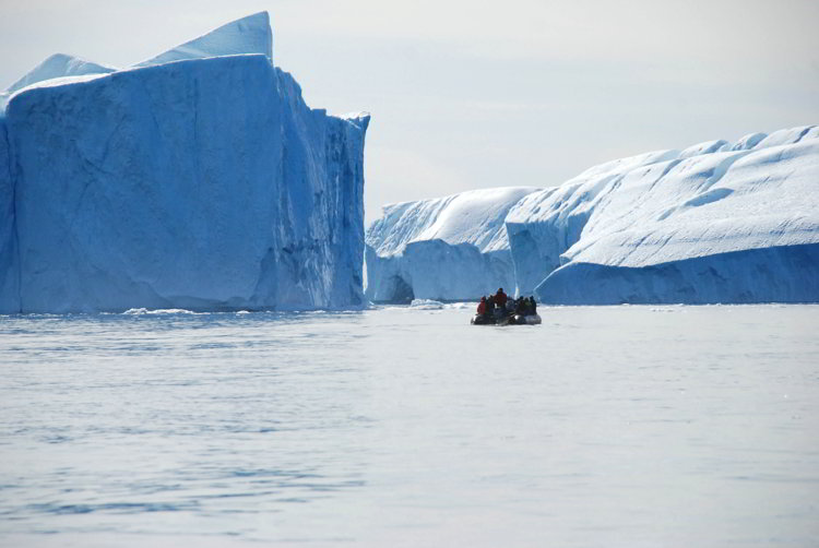 An image of a zodiac boat near large icebergs outside Ilulissat Greenland