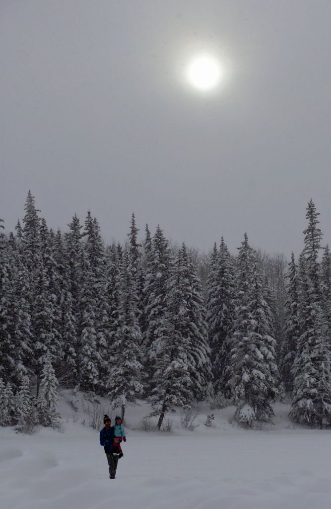 An image of a man holding a little girl in his arms on a snowy Pyramid Lake in Jasper National Park in Alberta, Canada - Jasper in Winter - Stunning Photos