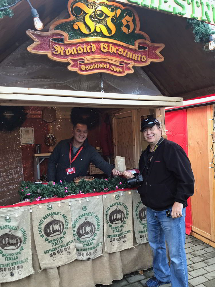 An image of a man purchasing roasted chestnuts at the Vancouver Christmas Market in Vancouver, BC Canada - Vancouver Christmas Lights