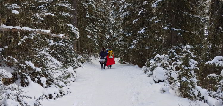 An image of a couple walking through a forest of snow covered trees on the ink pots hike in Banff National Park, Alberta - Johnston Canyon Winter Hike and ink pots hike