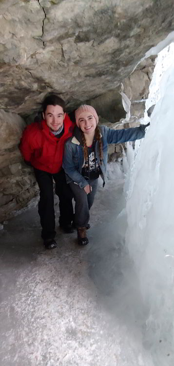 An image of a couple standing behind a frozen waterfall in Banff National Park, Alberta - Johnston Canyon Winter Hike and ink pots hike