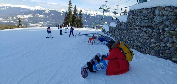 An image of a snow boarder adjusting his board at Marmot Basin in Jasper, Alberta - Jasper Skiing