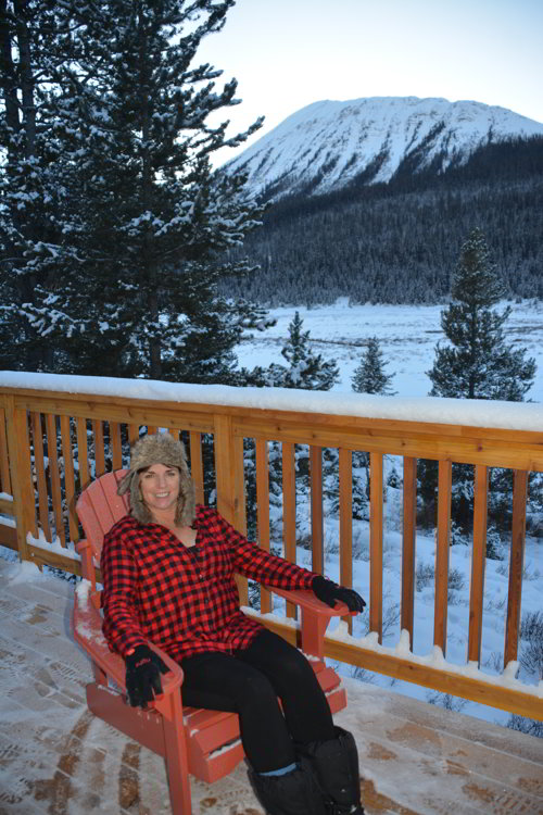 Image of a women sitting in a chair on a deck in the mountains - Avoid the Winter Blues.