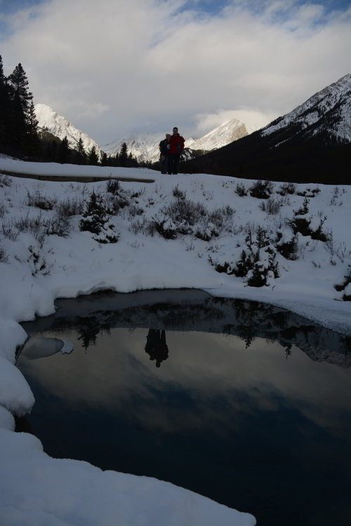 Image of a couple standing arm in arm over looking the ink pots in Johnston Canyon in Banff National Park - Avoid the Winter Blues.