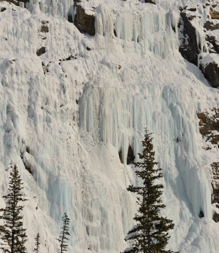Image of an ice floe on the side of a mountain along Icefields Parkway with an ice climber scaling the ice.