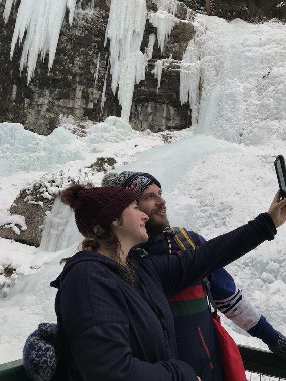 Image of a couple taking a selfie of themselves in Johnston Canyon in Banff National Park - Avoid the Winter Blues.