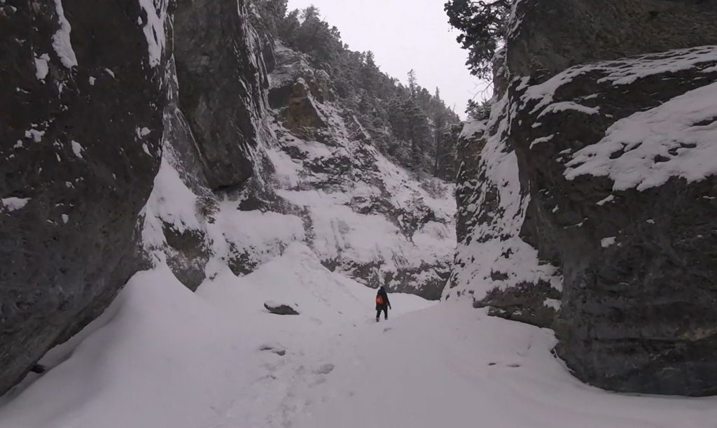 An image of a hiker walking through the frozen Grotto Canyon hike near Canmore, Alberta.