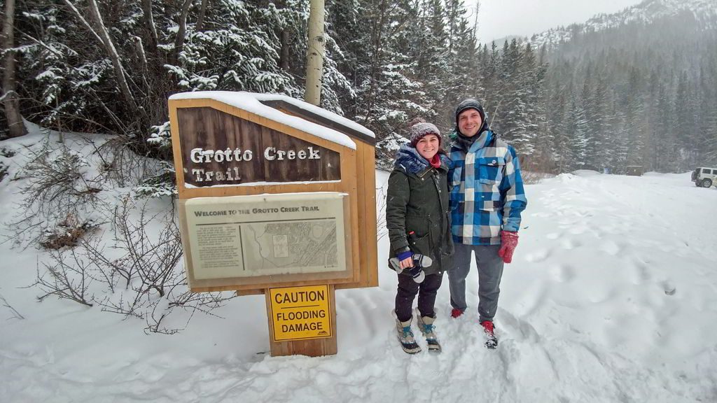 An image of two hikers standing in front of the Grotto Creek Canyon Trailhead sign near Canmore, Alberta - Grotto Canyon Hike