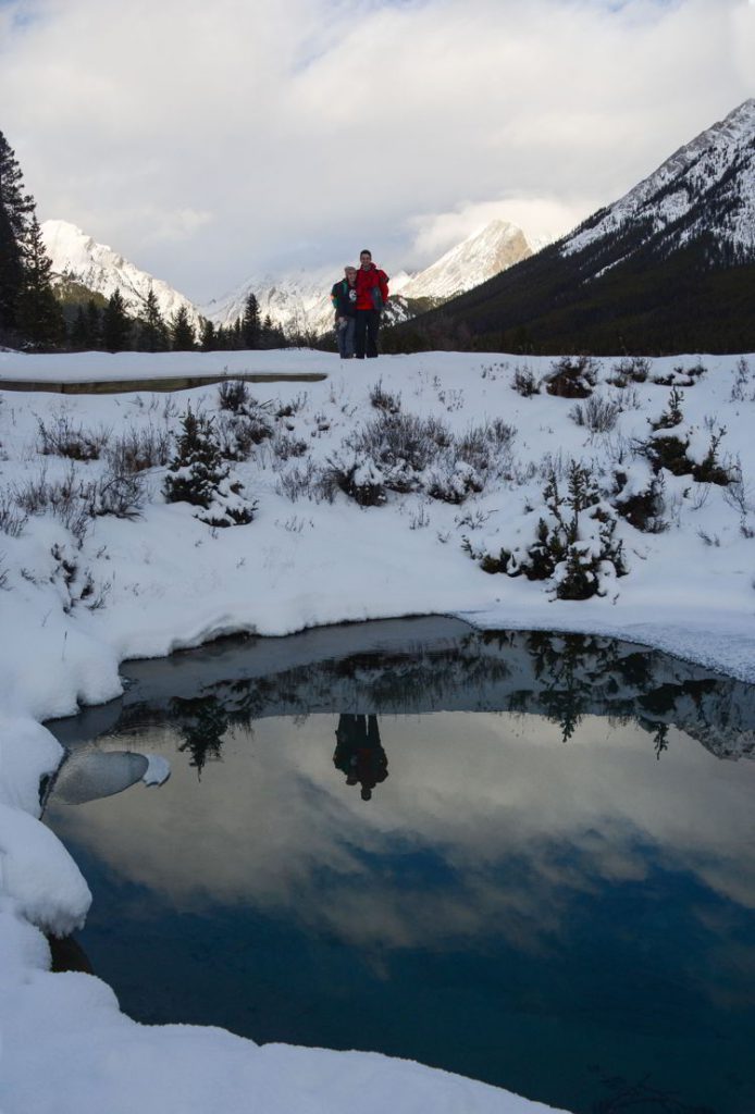 An image of a couple standing above the ink pots in winter in Banff National Park, Alberta - Johnston Canyon Winter Hike and ink pots hike