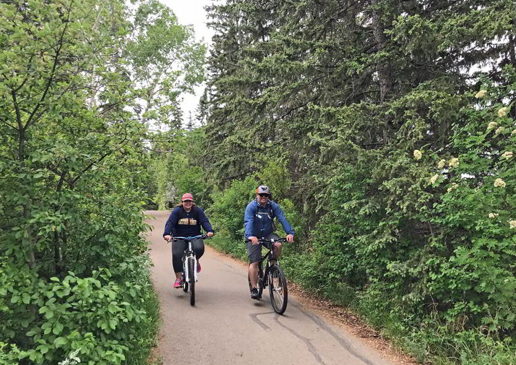 An image of two people cycling on the trails in Waskasoo Park in Red Deer, Alberta, Canada. 