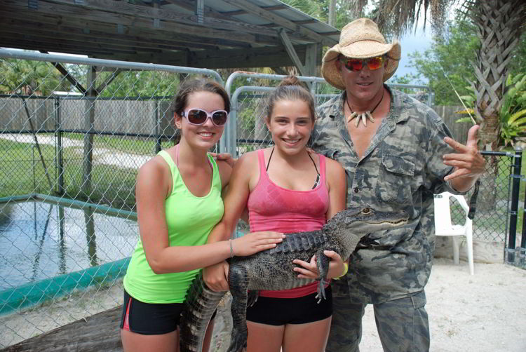An image of two girls and a man holding a baby alligator at Wooter's animal sanctuary in the Florida Everglades.