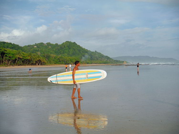 An image of a surfer carrying his board to the beach in Costa Rica. 