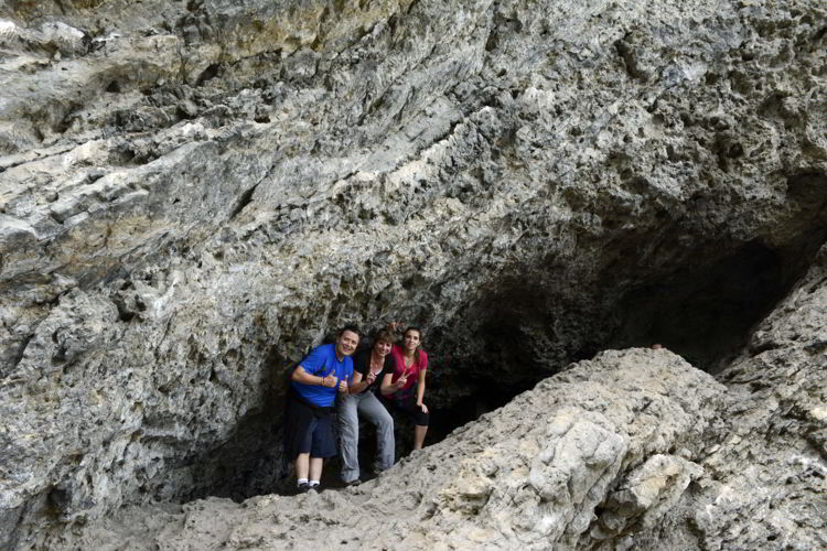 An image of three people standing inside a shallow cave on the Grassi Lakes hike near Canmore, Alberta in the Canadian Rockies.