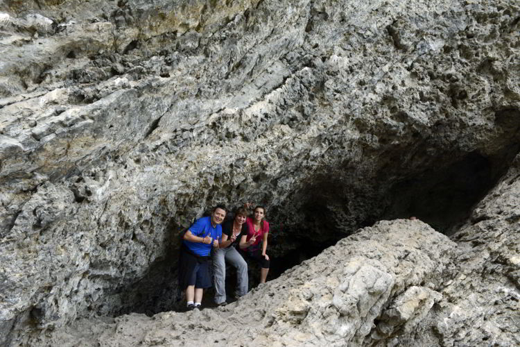 An image of three people standing inside a shallow cave on the Grassi Lakes hike near Canmore, Alberta in the Canadian Rockies. 