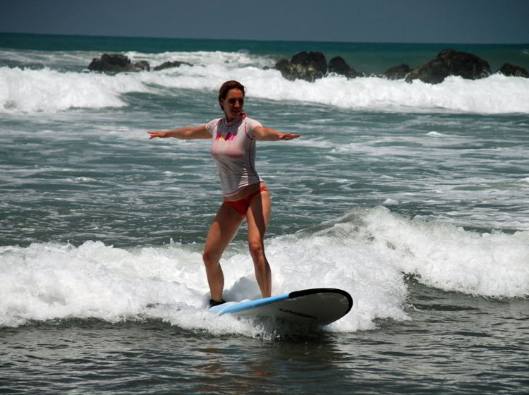 An image of a woman riding a wave at surf camp in Costa Rica.