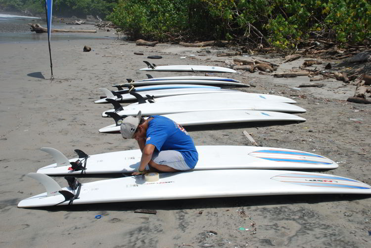 An image of a surf instructor preparing the boards at surf school in Costa Rica.