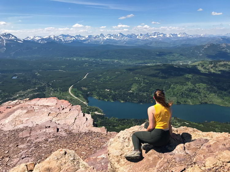 An image of a young woman taking in the view from the top of Table Mountain, Alberta.