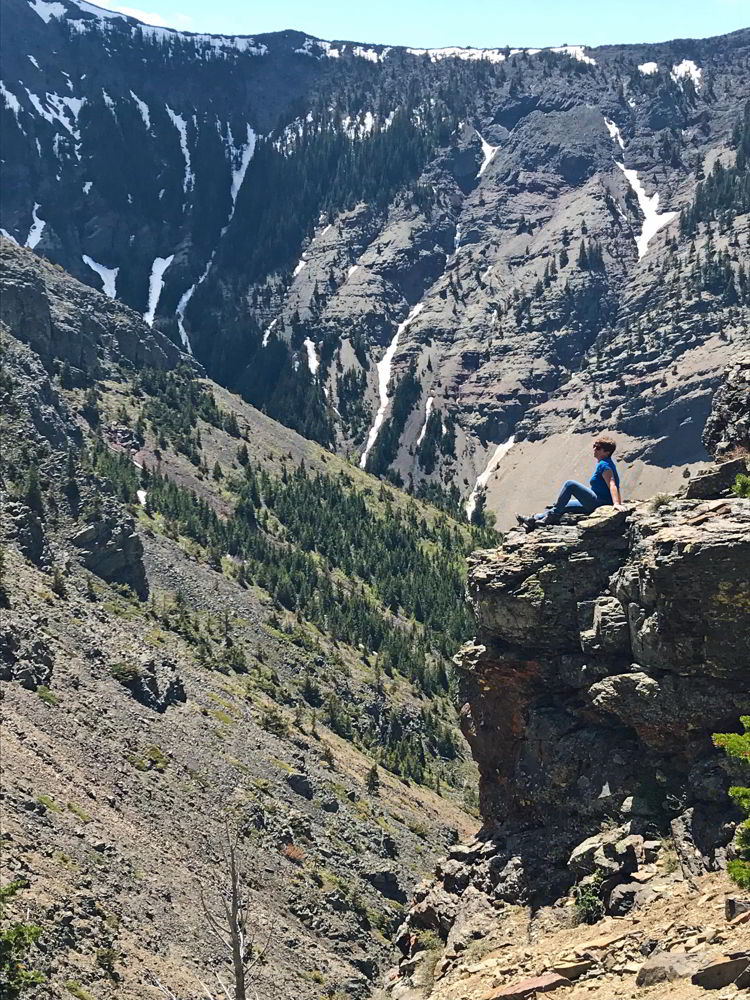 An image of a woman sitting on a rock outcropping partway up the Table Mountain hike in Alberta, Canada. 