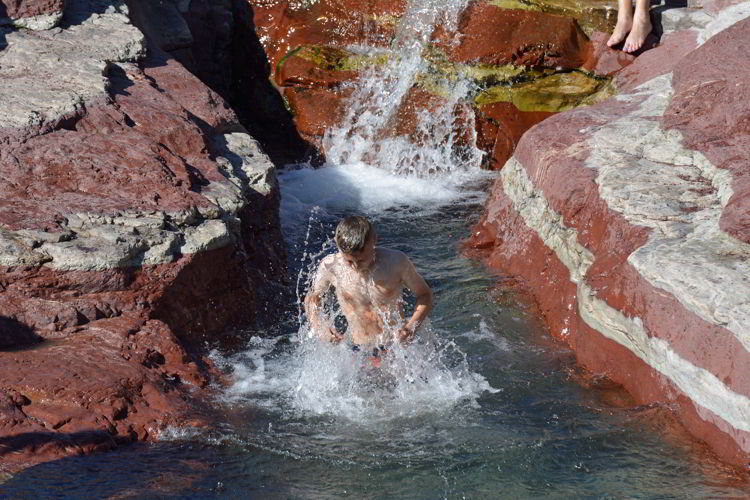 An image of a boy swimming in the icy cold waters of Red Rock Canyon in Waterton Lakes National Park in Alberta, Canada. 