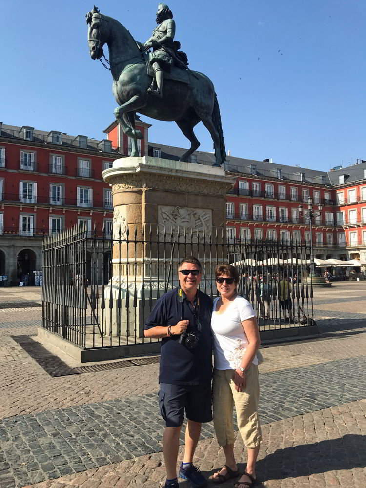 An image of two people standing in front of the statue of Phillip III in the centre of Plaza Mayor in Madrid, Spain. 