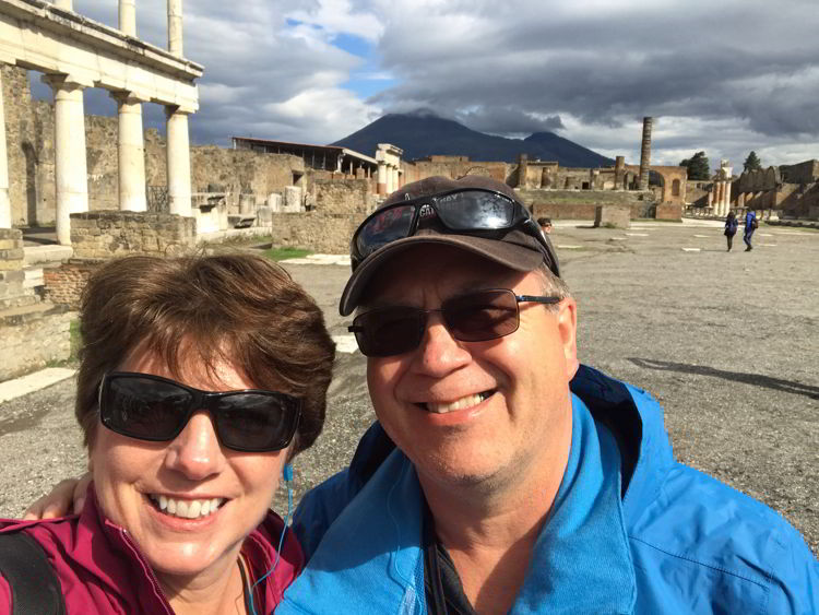 An image of two people standing in Pompeii with Mount Vesuvius in the background near Naples, Italy. 