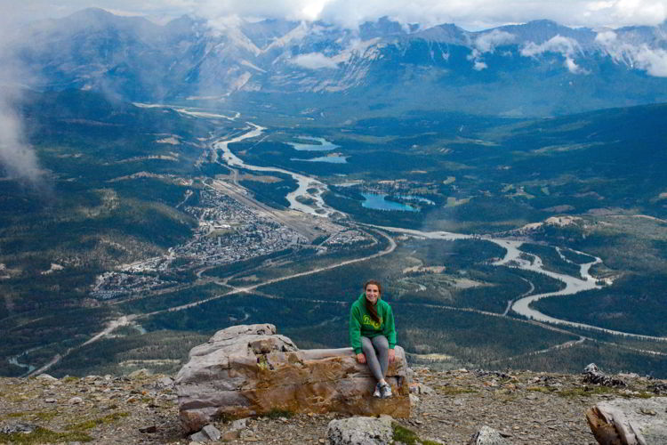 An image of a young woman sitting on a rock at the top of Whistler's Mountain in Jasper National Park, Alberta, Canada - Jasper hikes.