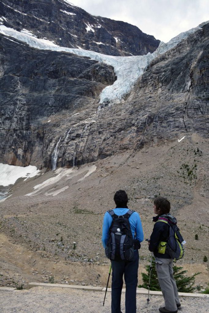 An image of two people looking up at the Angel Glacier on the Mount Edith Cavell trail in Jasper National Park - Jasper hikes. 