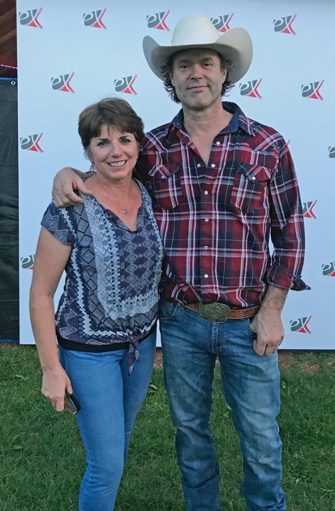 An image of a woman standing next to Corb Lund at Whoop-up Days in Lethbridge, Alberta.  