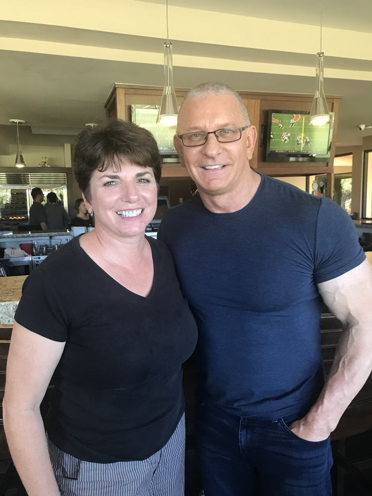 An image of a woman standing next to Robert Irvine at the Hawaii Food and Wine Festival in 2018. 