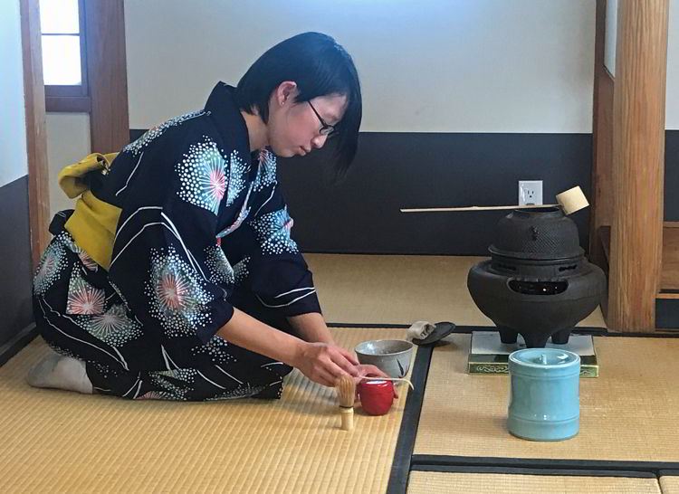 An image of a woman pouring tea in a traditional Japanese tea ceremony at the Nikka Yuko Japanese Gardens in Lethbridge, Alberta
