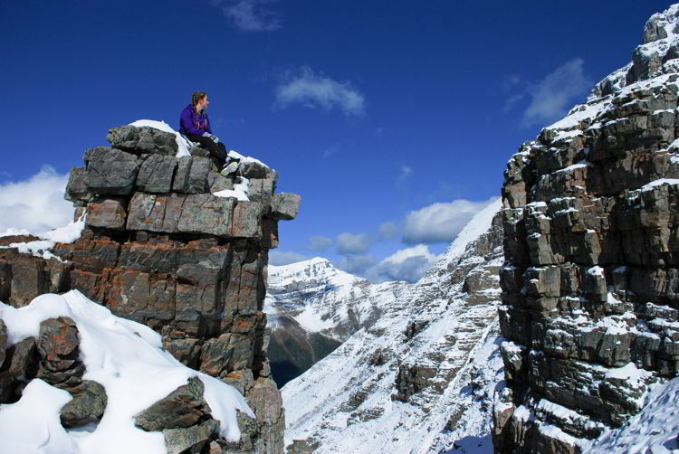 An image of a young woman sitting on a rock outcropping near the top of Sentinel Pass in Banff National Park, Alberta, Canada. 