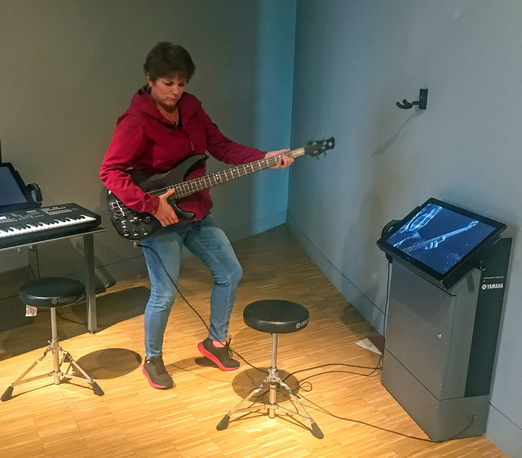 An image of a woman playing a bass guitar at Studio Bell in Calgary, Alberta Canada. 