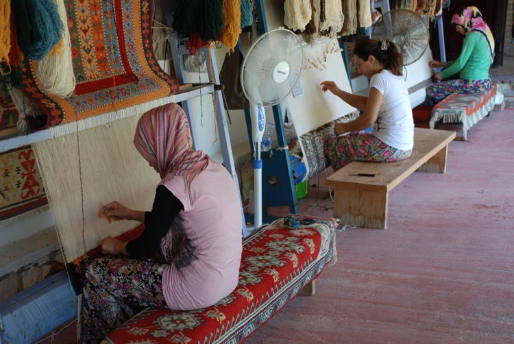 An image of women weaving rugs in Turkey. 