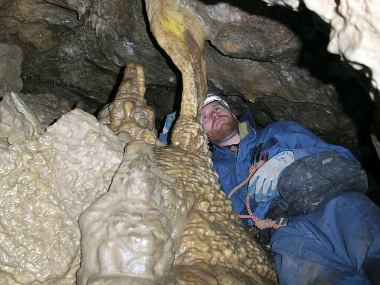 An image of a man looking at a rock formation inside the Rat's Nest Cave near Canmore, Alberta - Canmore Cave Tours