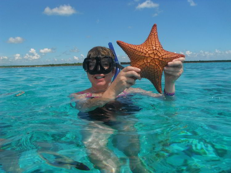 An image of a woman holding a starfish while snorkeling in Cozumel, Mexico - Riviera Maya excursions. 
