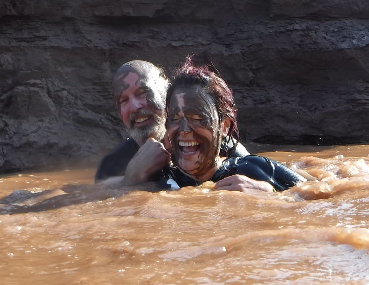 An image of two people covered in mud swimming in the Schubenacadie River in Nova Scotia. 