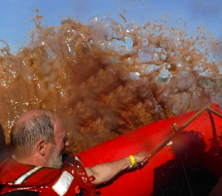 An image of a boat hitting the tidal bore on a tidal bore rafting excursion in Nova Scotia, Canada.